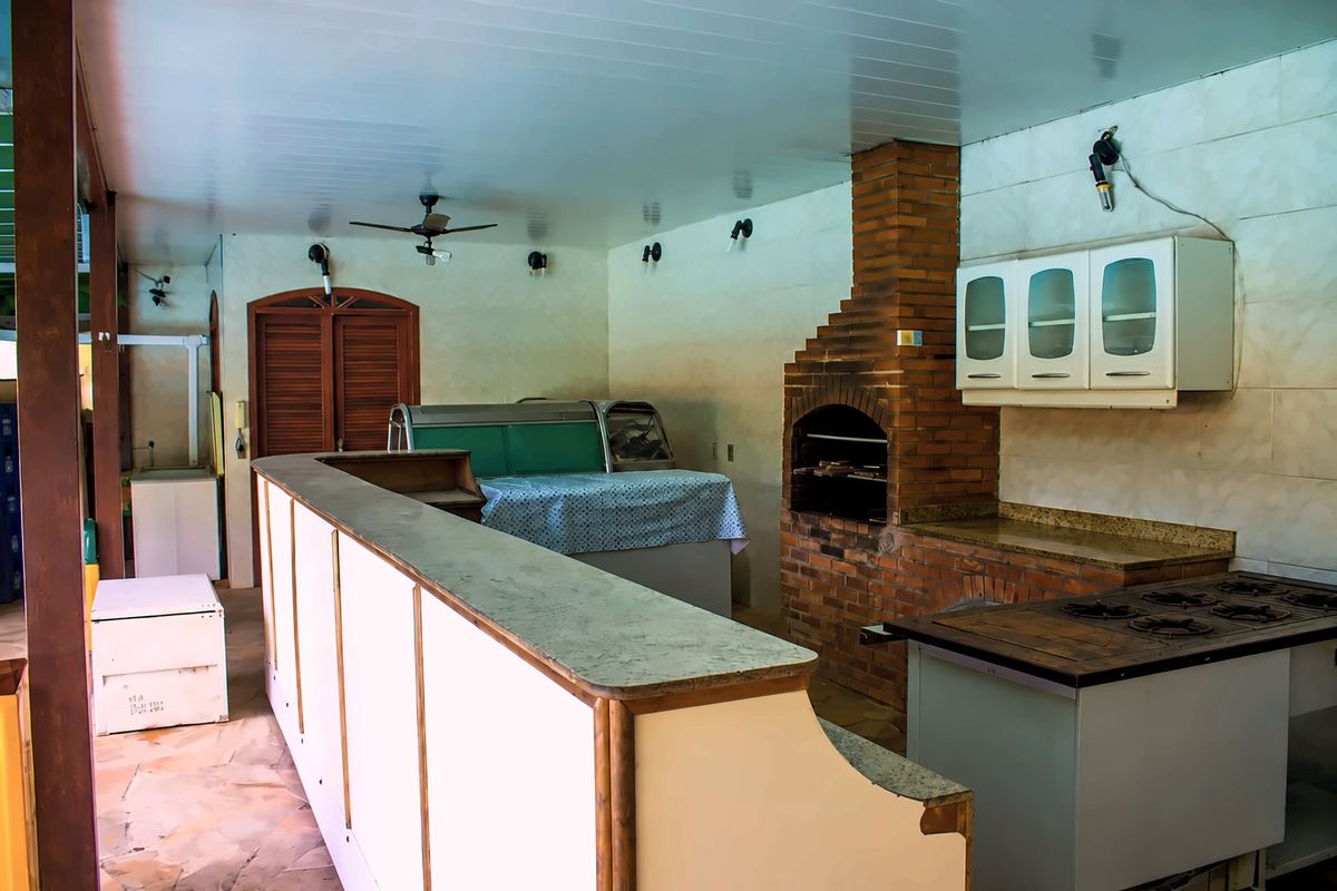 Área gourmet com balcão, churrasqueira de tijolos e fogão industrial